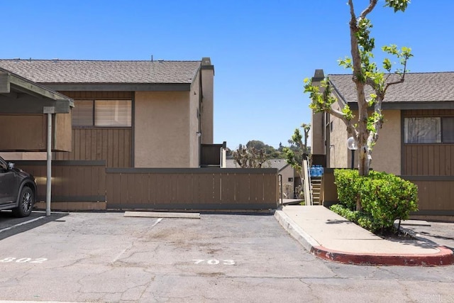 7780 Parkway Dr Unit 703, La Mesa, CA 91942 - view of side of home featuring uncovered parking, stucco siding, and a shingled roof