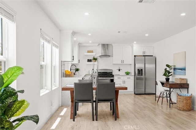 453 N Walker Ave, San Pedro, CA 90732 - kitchen with appliances with stainless steel finishes, wall chimney exhaust hood, light wood-type flooring, white cabinets, and recessed lighting