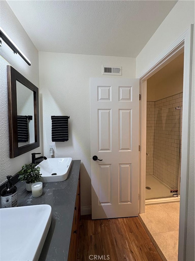 46 Echo Run Unit 16, Irvine, CA 92614 - full bathroom featuring a shower stall, double vanity, wood finished floors, and a textured ceiling