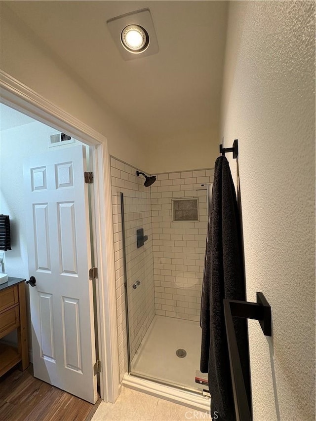 46 Echo Run Unit 16, Irvine, CA 92614 - bathroom with a stall shower, vanity, a textured wall, and wood finished floors