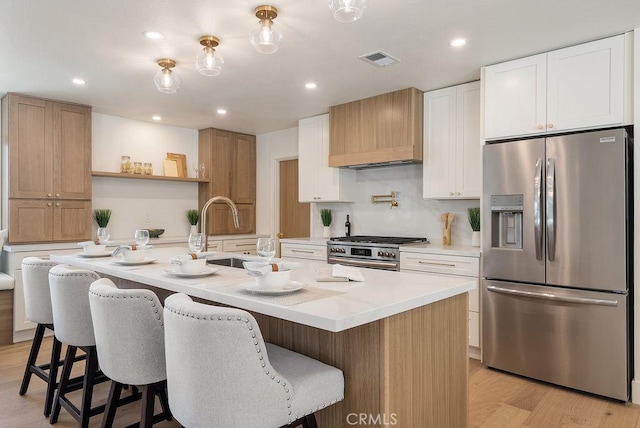 1932 Chapman Rd, Claremont, CA 91711 - kitchen with appliances with stainless steel finishes, custom range hood, light countertops, light wood-type flooring, and a kitchen bar