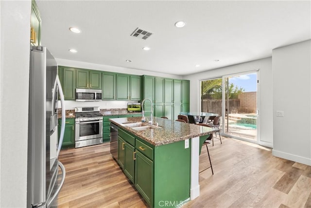 29889 Warm Sands Dr, Menifee, CA 92584 - kitchen with green cabinetry, stainless steel appliances, a sink, a kitchen bar, and light wood finished floors