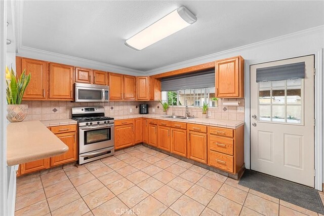 1040 W 3rd St, Pomona, CA 91766 - kitchen featuring stainless steel appliances, a sink, ornamental molding, tasteful backsplash, and light tile patterned flooring