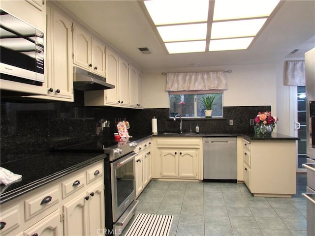 1575 Santa Inez Ct, Merced, CA 95340 - kitchen featuring appliances with stainless steel finishes, under cabinet range hood, a sink, a peninsula, and dark countertops