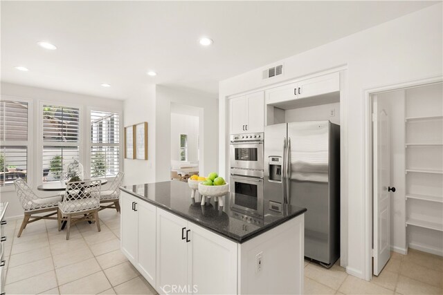 19139 Chandon Ln, Huntington Beach, CA 92648 - kitchen featuring appliances with stainless steel finishes, white cabinetry, dark stone countertops, light tile patterned floors, and recessed lighting