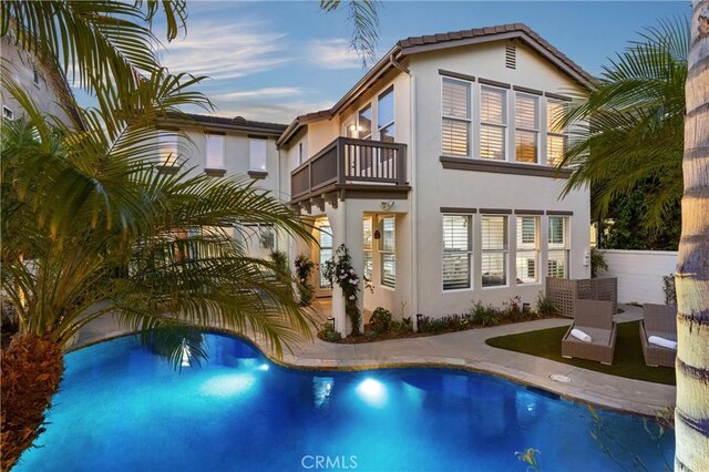 19139 Chandon Ln, Huntington Beach, CA 92648 - rear view of house with a balcony, stucco siding, and an outdoor pool