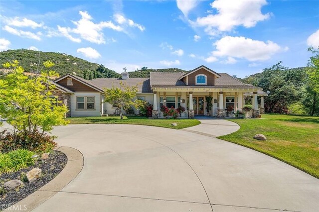41275 Hacienda Dr, Murrieta, CA 92562 - view of front facade featuring covered porch, curved driveway, a front lawn, and stone siding