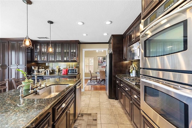 40678 Alondra Dr, Murrieta, CA 92562 - kitchen with stainless steel appliances, backsplash, dark brown cabinetry, a sink, and glass insert cabinets
