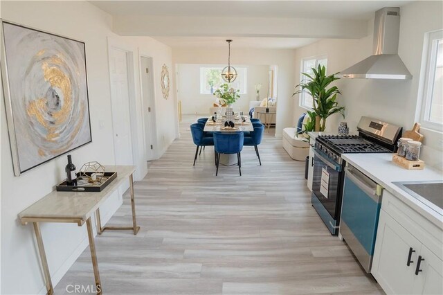 14609 Clark St, Baldwin Park, CA 91706 - kitchen with wall chimney exhaust hood, stainless steel gas range oven, dishwashing machine, light wood-type flooring, and white cabinetry