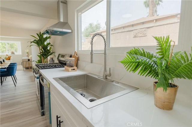 14609 Clark St, Baldwin Park, CA 91706 - kitchen featuring wall chimney range hood, a sink, stainless steel range with gas stovetop, white cabinetry, and light countertops