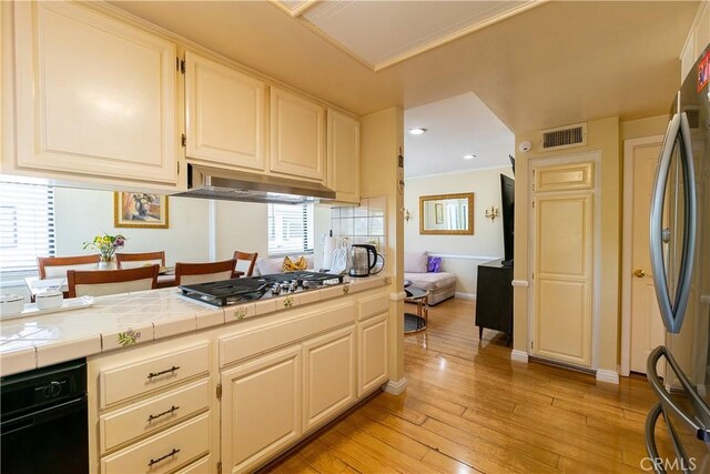 18759 Hatteras St Unit 25, Tarzana, CA 91356 - kitchen with tile counters, light wood finished floors, stainless steel appliances, crown molding, and baseboards