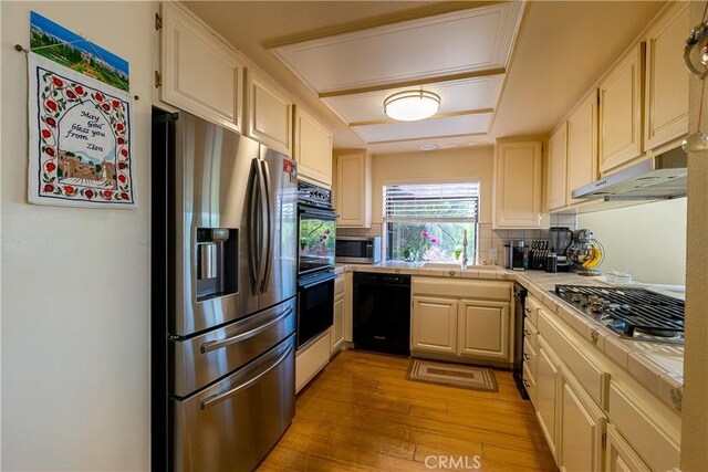 18759 Hatteras St Unit 25, Tarzana, CA 91356 - kitchen featuring black appliances, tile counters, light wood-style floors, a sink, and under cabinet range hood