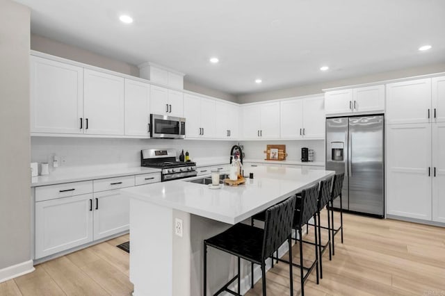 7902 Belluno Way, San Diego, CA 92126 - kitchen with stainless steel appliances, a sink, light wood-style floors, a breakfast bar area, and recessed lighting