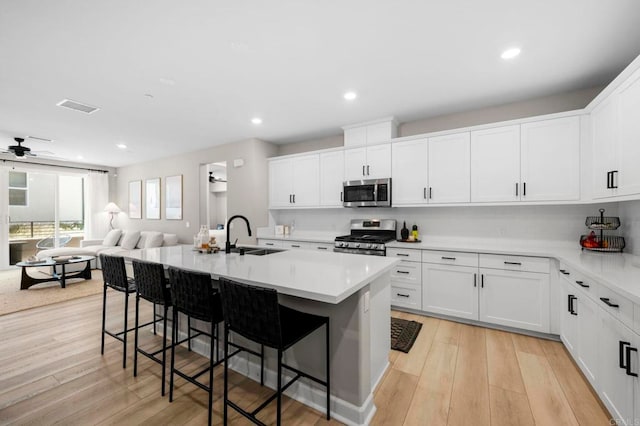 7902 Belluno Way, San Diego, CA 92126 - kitchen featuring appliances with stainless steel finishes, a sink, a breakfast bar area, open floor plan, and light countertops