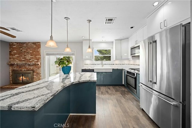 43220 51st St W, Quartz Hill, CA 93536 - kitchen with appliances with stainless steel finishes, a sink, wood finished floors, a brick fireplace, and a ceiling fan