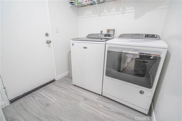 28217 Alton Way, Castaic, CA 91384 - laundry area featuring washer and dryer, light wood-type flooring, and baseboards
