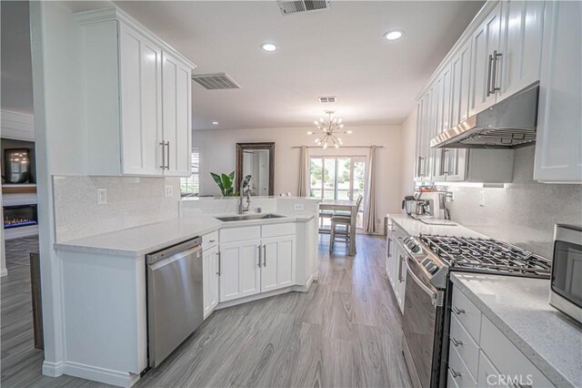 28217 Alton Way, Castaic, CA 91384 - kitchen featuring appliances with stainless steel finishes, under cabinet range hood, a sink, a chandelier, and white cabinets
