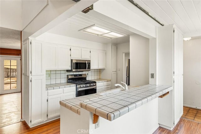 2631 San Jose St, Chico, CA 95973 - kitchen with appliances with stainless steel finishes, a sink, tile counters, and light wood-style floors