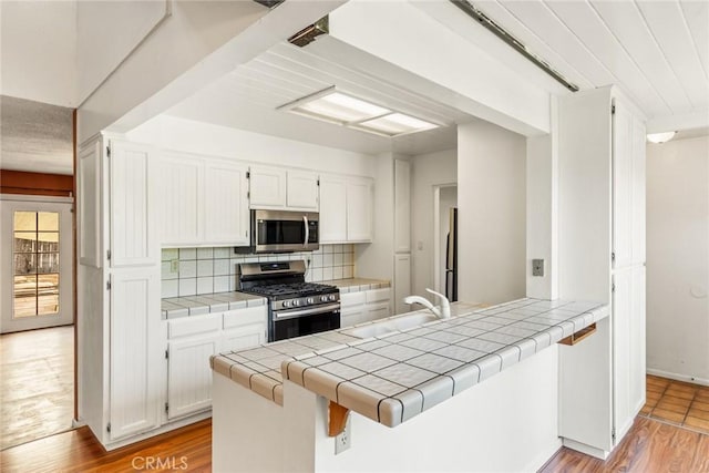 2631 San Jose St, Chico, CA 95973 - kitchen featuring appliances with stainless steel finishes, tile countertops, white cabinets, and light wood-style flooring
