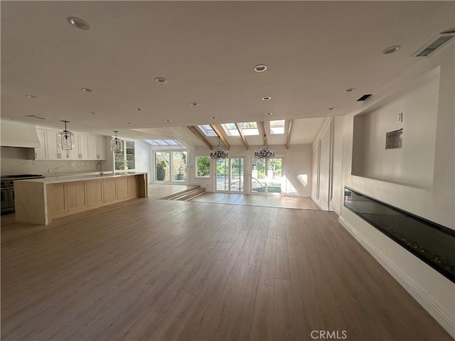 23128 Park Sorrento, Calabasas, CA 91302 - unfurnished living room with a glass covered fireplace, wood finished floors, a sink, recessed lighting, and a chandelier
