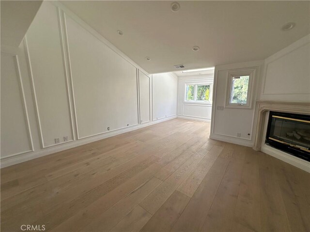 23128 Park Sorrento, Calabasas, CA 91302 - unfurnished living room with light wood-style floors, a glass covered fireplace, a decorative wall, and vaulted ceiling