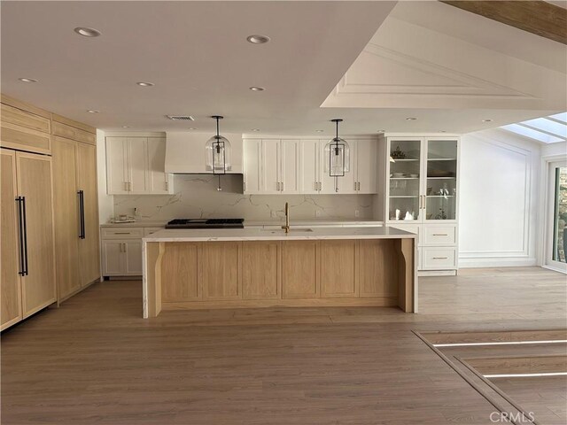 23128 Park Sorrento, Calabasas, CA 91302 - kitchen with light wood-style flooring, recessed lighting, backsplash, a large island with sink, and light countertops