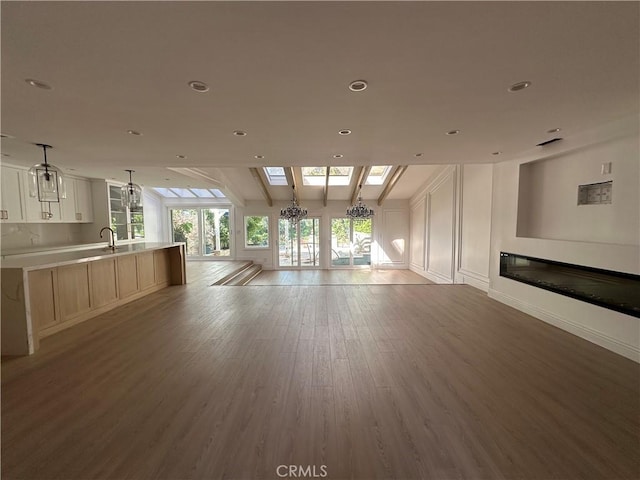 23128 Park Sorrento, Calabasas, CA 91302 - unfurnished living room featuring light wood-type flooring, a glass covered fireplace, recessed lighting, a sink, and beamed ceiling