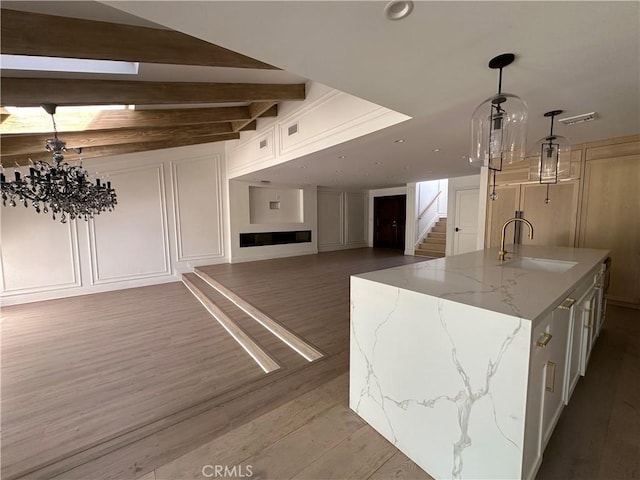 23128 Park Sorrento, Calabasas, CA 91302 - kitchen with a sink, dark wood-type flooring, a chandelier, a decorative wall, and light stone countertops