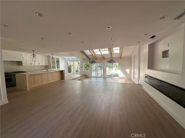 23128 Park Sorrento, Calabasas, CA 91302 - unfurnished living room featuring a glass covered fireplace, wood finished floors, recessed lighting, and a chandelier