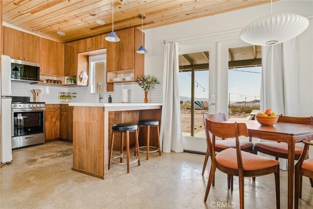 79124 Valle Vista Rd Unit 29, Palms, CA 92277 - kitchen featuring appliances with stainless steel finishes, brown cabinets, open shelves, wood ceiling, and light countertops