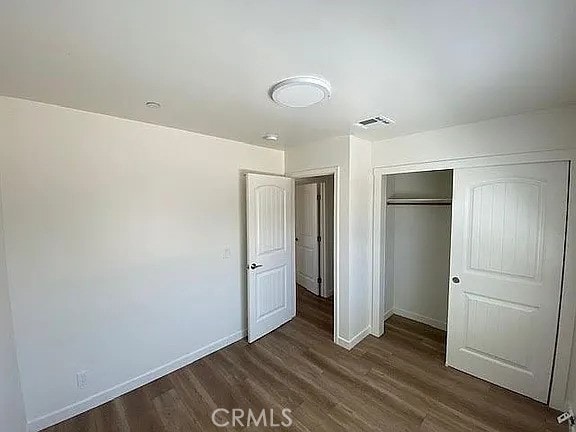 1340 Mariposa, Ridgecrest, CA 93555 - unfurnished bedroom featuring dark wood-style flooring, baseboards, and a closet