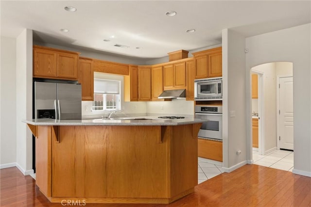 1095 Glenwood Ln, Willows, CA 95988 - kitchen with stainless steel appliances, arched walkways, a kitchen breakfast bar, under cabinet range hood, and recessed lighting