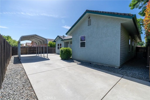 1095 Glenwood Ln, Willows, CA 95988 - view of side of home featuring a detached carport, a fenced backyard, driveway, and stucco siding