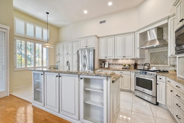 6056 Piros Way, Oceanside, CA 92056 - kitchen with stainless steel appliances, wall chimney exhaust hood, decorative backsplash, a center island with sink, and decorative light fixtures