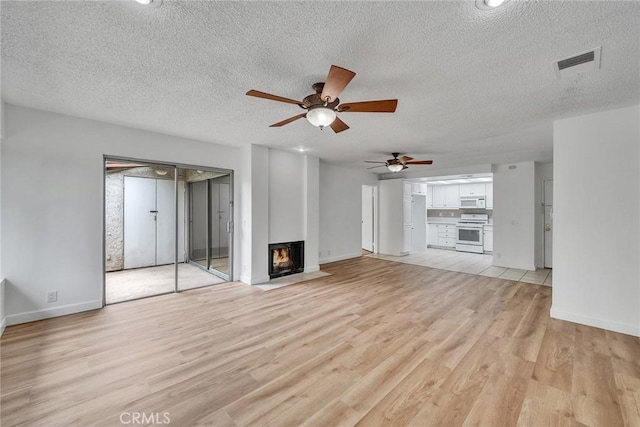 901 Golden Springs Dr Unit D13, Diamond Bar, CA 91765 - unfurnished living room with light wood-style floors, ceiling fan, a lit fireplace, baseboards, and a textured ceiling