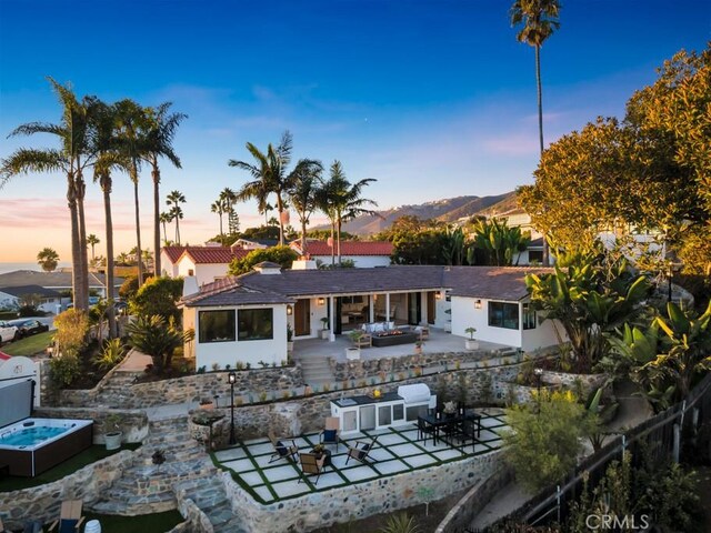 10 Camel Pt, Laguna Beach, CA 92651 - back of house at dusk with a patio area, an outdoor hangout area, and a mountain view