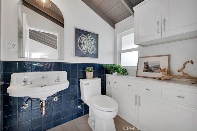 10 Camel Pt, Laguna Beach, CA 92651 - bathroom featuring lofted ceiling, tile walls, toilet, a wainscoted wall, and a sink