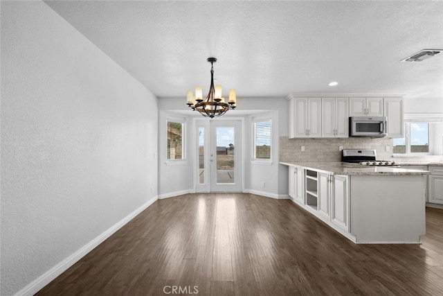 8225 W W Ave E4, Lancaster, CA 93536 - kitchen with stainless steel microwave, stove, a chandelier, baseboards, and a textured ceiling