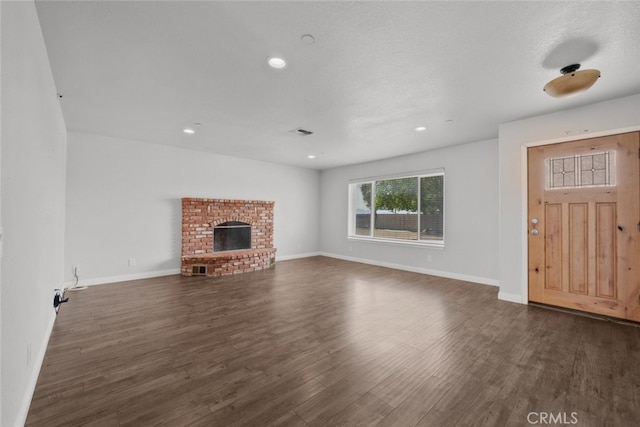 8225 W W Ave E4, Lancaster, CA 93536 - unfurnished living room with dark wood-type flooring, a brick fireplace, recessed lighting, and baseboards