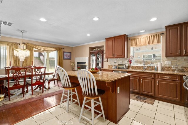 16290 Via Ultimo, Moreno Valley, CA 92551 - kitchen featuring a sink, a kitchen island, tasteful backsplash, light tile patterned floors, and ornamental molding
