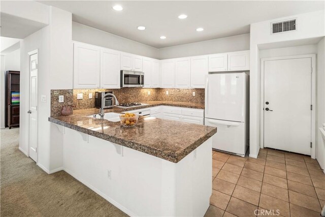 26974 Colonial Ln, Valencia, CA 91355 - kitchen with white appliances, a peninsula, recessed lighting, white cabinets, and a sink