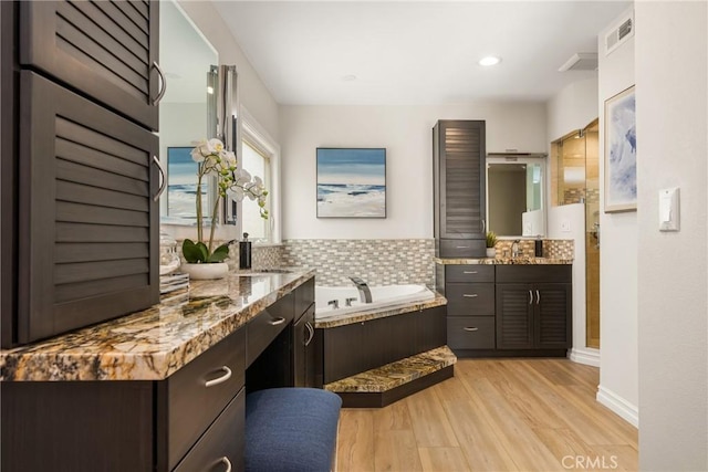 13061 Rosalind Dr, North Tustin, CA 92705 - full bathroom featuring a garden tub, two vanities, wood finished floors, decorative backsplash, and a walk in shower