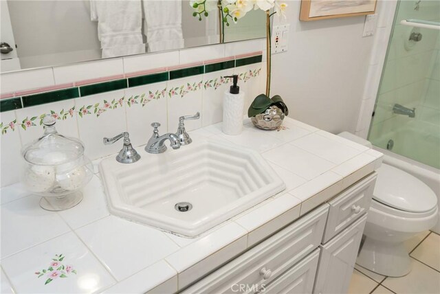 13061 Rosalind Dr, North Tustin, CA 92705 - bathroom featuring toilet, vanity, backsplash, and bath / shower combo with glass door