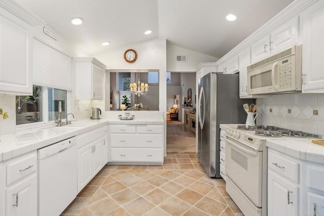 7414 Lantana, Carlsbad, CA 92011 - kitchen with white appliances, tile counters, vaulted ceiling, a sink, and white cabinets