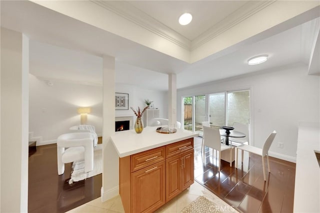 187 S Catalina Ave Unit 4, Pasadena, CA 91106 - kitchen with crown molding, a lit fireplace, light countertops, baseboards, and brown cabinetry
