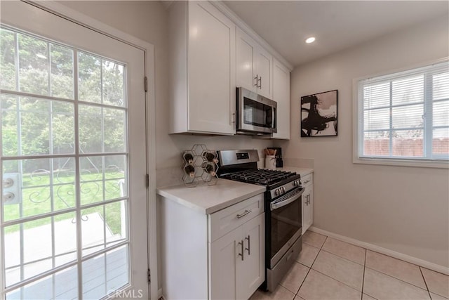 7704 Isis Ave, Los Angeles, CA 90045 - kitchen with stainless steel appliances, baseboards, light countertops, light tile patterned floors, and white cabinets