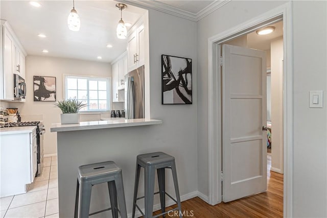 7704 Isis Ave, Los Angeles, CA 90045 - kitchen featuring appliances with stainless steel finishes, white cabinetry, a kitchen bar, light countertops, and a peninsula