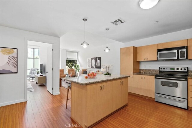 630 W 6th St Unit 215, Los Angeles, CA 90017 - kitchen with appliances with stainless steel finishes, light wood-type flooring, a kitchen island, light brown cabinets, and a breakfast bar area