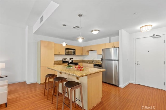 630 W 6th St Unit 215, Los Angeles, CA 90017 - kitchen featuring stainless steel appliances, light wood-style floors, a breakfast bar, a center island, and baseboards
