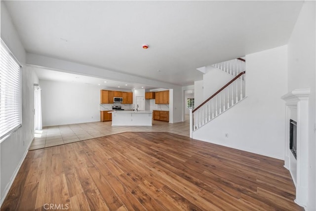 1568 Burns Ln, San Jacinto, CA 92335 - unfurnished living room featuring light wood finished floors, stairway, a sink, and a fireplace